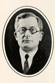 Formal portrait of William Empson, clean-shaven, wearing eyeglasses and dressed in a coat and tie