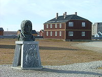 Het Noordpoolhotel in Ny-Ålesund en de buste van Roald Amundsen