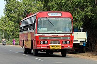 A bus in a road with trees in the background